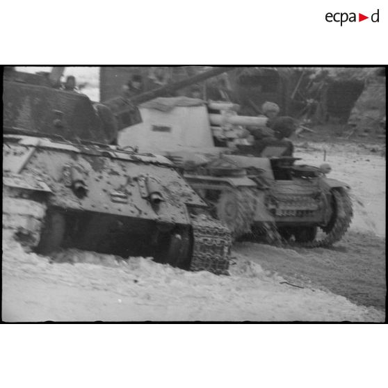 Un Sd.kfz.124 "Wespe" passe devant un char soviétique T-34 détruit.
