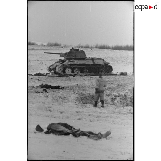 Un cadavre de soldat soviétique, au second plan, un T-34 détruit.