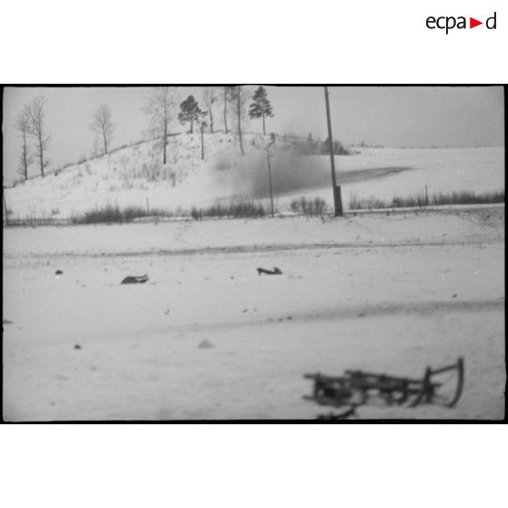 Panache et fumées générées par une explosion, au premier plan un traineau abandonné.