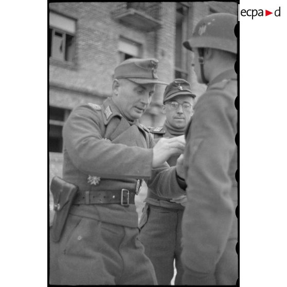 Le commandant (Major) Horst-Wolf Hoppe remet une décoration à un caporal, au centre le lieutenant de réserve Julius Stehler.