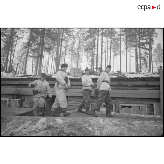 Des officiers sortent d'un bunker, le premier porte un calot noir qui identifie les troupes blindées allemandes.
