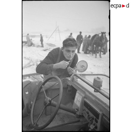 Un fantassins se rase en s'aidant d'un rétro-viseur d'un véhicule amphibie Schwimmwagen.