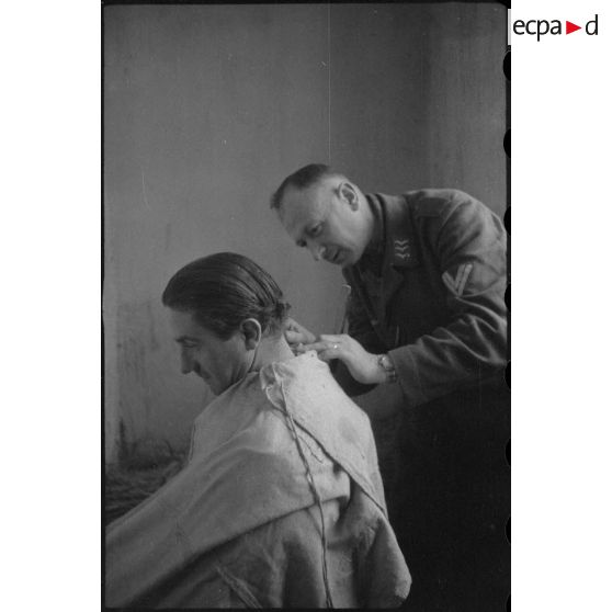Un fantassin de la Luftwaffe coupe les cheveux d'un camarade.