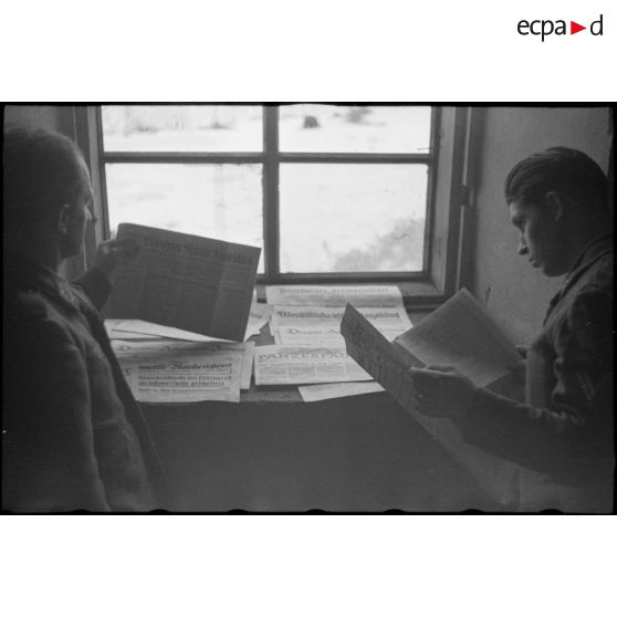 Des fantassins de la Luftwaffe consultent les titres de la presse allemande.