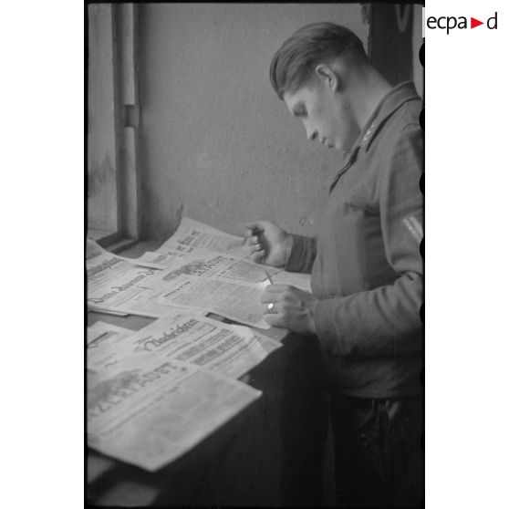 Des fantassins de la Luftwaffe consultent les titres de la presse allemande.