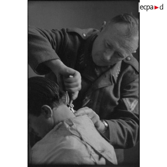 Un fantassin de la Luftwaffe coupe les cheveux d'un camarade.