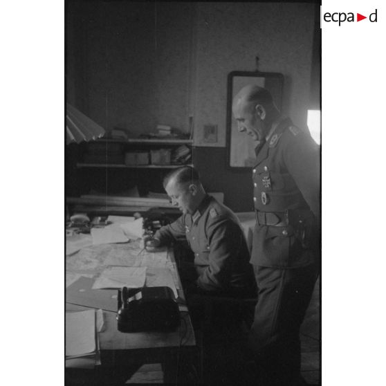 Un briefing dans un bureau, deux colonels se concentrent sur une carte.