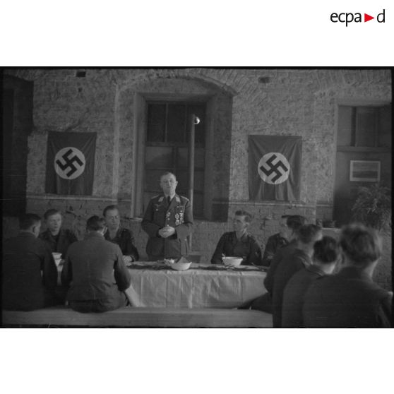 Le général (Generalleutnant) Robert Pistorius partage un repas avec des hommes 4e division d'infanterie de l'armée de l'air allemande après avoir prononcé un discours.