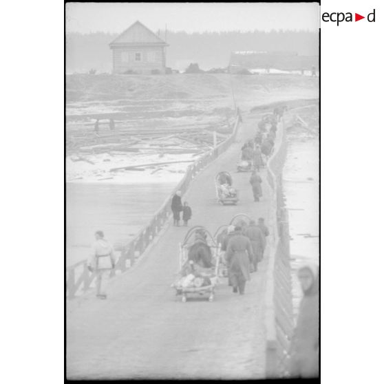 La traversée d'un pont par des soldats et des civils.