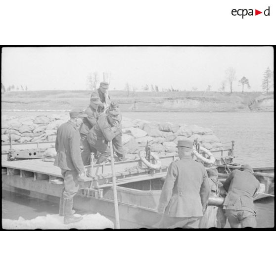 Après la traversée d'une rivière sur un ponton (Brückengerät), des sacs postaux sont déchargés.