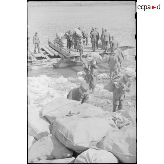 Après la traversée d'une rivière sur un ponton (Brückengerät), des sacs postaux sont déchargés.