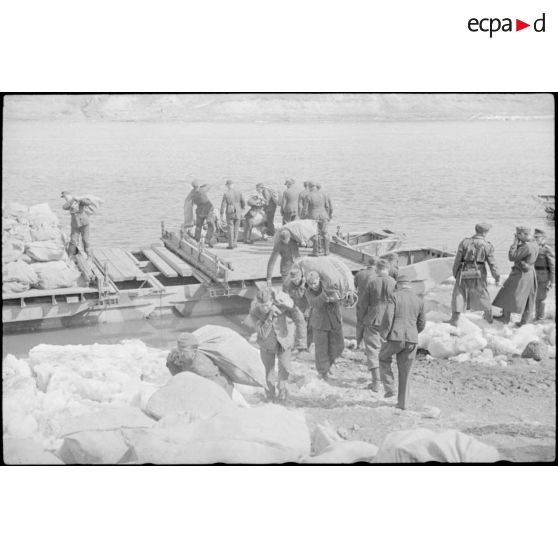 Après la traversée d'une rivière sur un ponton (Brückengerät), des sacs postaux sont déchargés.