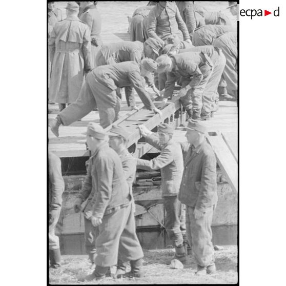 Déploiement de poutres métalliques du ponton (Brückegerät) pour faire descendre ou monter un véhicule.