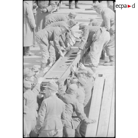 Déploiement de poutres métalliques du ponton (Brückegerät) pour faire descendre ou monter un véhicule.