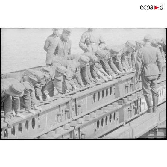 Déploiement de poutres métalliques du ponton (Brückegerät) pour faire descendre ou monter un véhicule.