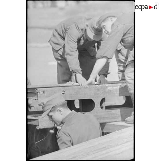 Déploiement de poutres métalliques du ponton (Brückegerät) pour faire descendre ou monter un véhicule.