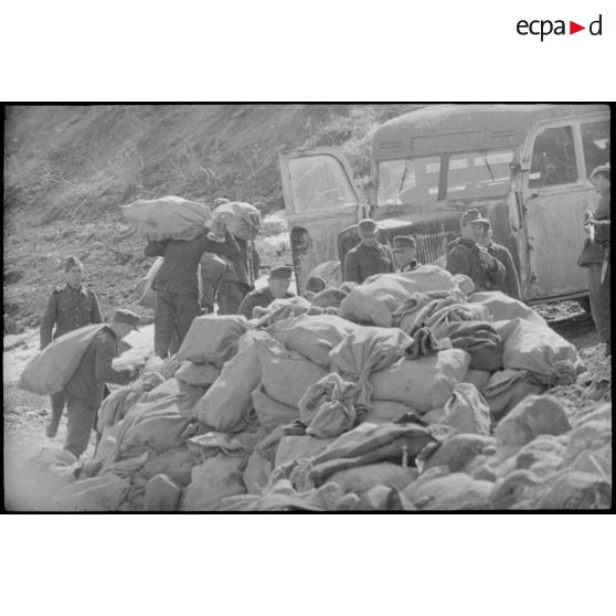 Aprés avoir été déchargés, des sacs postaux sont portés jusqu'à un bus qui assure le transport vers les destinataires.