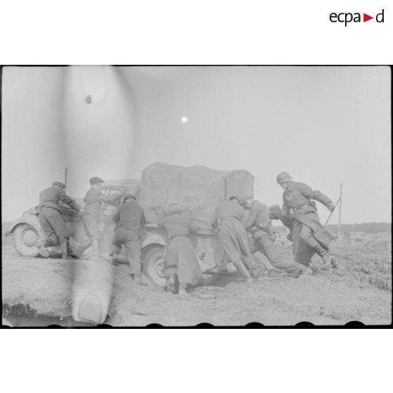 Une camionnette qui vient de s'embourber doit être poussée par des soldats.