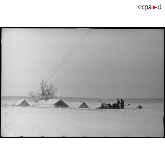 Une pièce de DCA légère de 2 cm FlaK placée à proximité d'un village.