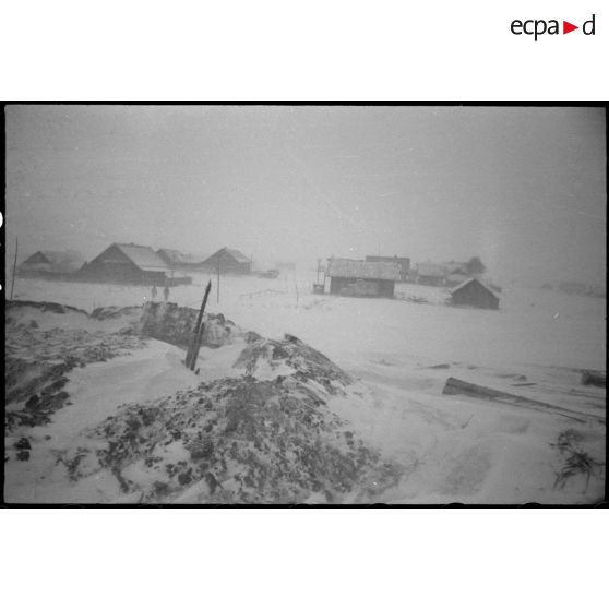 Un village sous une tempête de neige, les isbas sont certainement occupés par les soldats allemands.