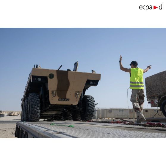 Un soldat du 5e régiment de cuirassiers (RC) guide le chargement d'un véhicule blindé de combat d'infanterie (VBCI) à bord d'un porte-engins blindé (PEB) émirien à Zayeb military city, aux Emirats arabes unis.