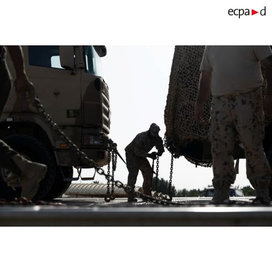Un soldat émirien fixe des véhicules du 5e régiment de cuirassiers (RC) à bord d'un porte-engin blindé (PEB) à Zayeb military city, aux Emirats arabes unis.