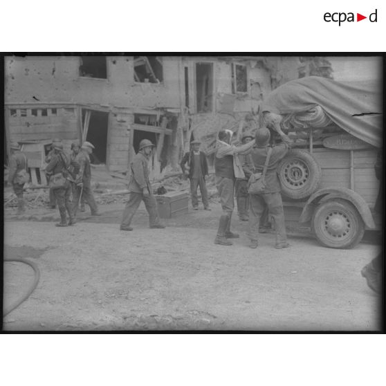 Des volontaires de la défense passive aident des civils à charger d'affaires personnelles un camion.