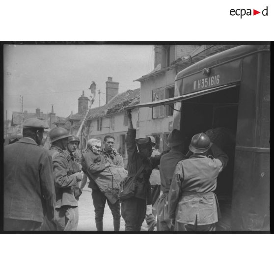 Après un bombardement allemand dans un village, des soldats évacuent une femme âgée blessée dans une ambulance.