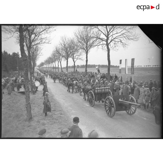 Sur une route, les troupes polonaises (75 mm M1897 hippomobile) défilent devant les officiels civils et militaires, polonais et français.