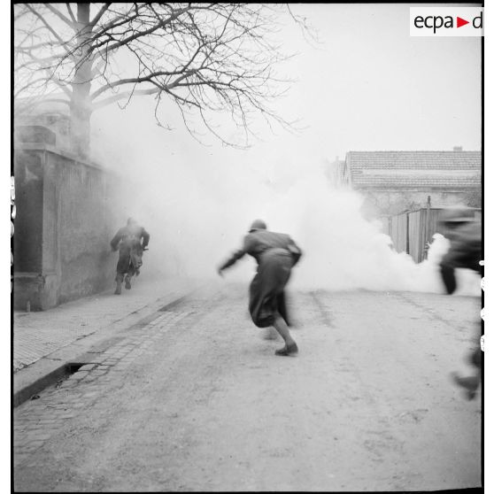 Des chasseurs du peloton spécial du 3e régiment de chasseurs d'Afrique (3e RCA) montent à l'assaut d'une habitation, dissimulés par la fumée de grenades fumigènes.