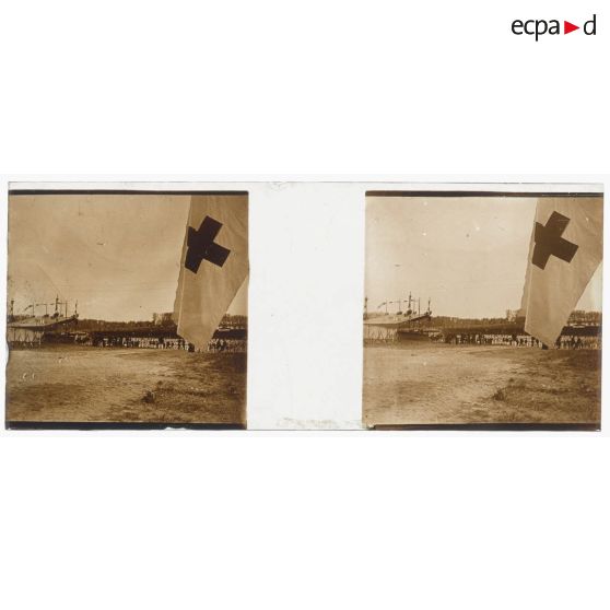 [Cérémonie militaire à Longchamp ? : vue générale avec drapeau à croix rouge au premier plan].<br>