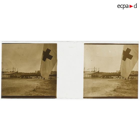 [Cérémonie militaire à Longchamp ? : vue générale avec drapeau à croix rouge au premier plan].<br> [Légende d'origine]