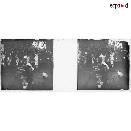 [Européens regardant Marocains (?) parqués derrière un grillage, comme dans une exposition coloniale].<br>