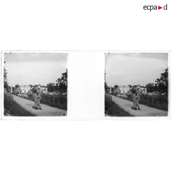 [Soldat, jumelles sur la poitrine, posant sur un chemin ; ruines à l'arrière-plan]. [Légende d'origine]