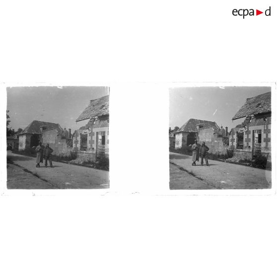 [Deux soldats posant dans une rue, devant des maisons en ruine]. [Légende d'origine]