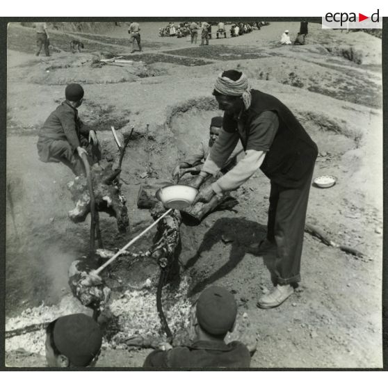 Ouled Haddada, avril 1961. Un méchoui. Cuisson sur feu de braises de deux moutons. [légende d'origine]
