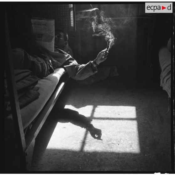 Contre-jour dans la chambre : tout le monde est consigné la veille de Noël 1960. Lire, fumer, tuer le temps… 92e RI, Clermont Ferrand. [légende d'origine]