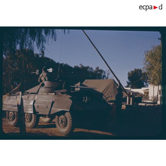 [Une auto-mitrailleuse M8 du 12e régiment de Dragons passe la barrière du camp].