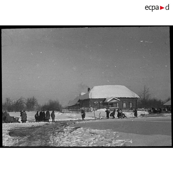 Medyn - Woronov [un groupe de personnes devant une habitation en bois dans la neige]. [Description en cours]