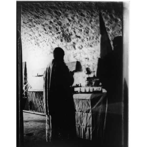 [Prêtre disant la messe sur un autel de campagne dans un intérieur].