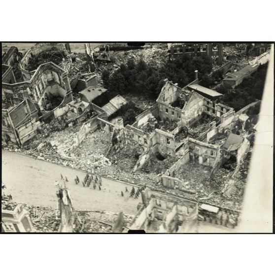 [Photographie aérienne du cortège d'un enterrement dans une ville en ruine].