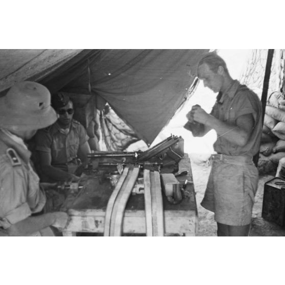 Sous une tente, des mécaniciens effectuent la maintenance d'une mitrailleuse MG-81 qui équipe les Junkers Ju-87 du Sturzkampfgechwader 3.