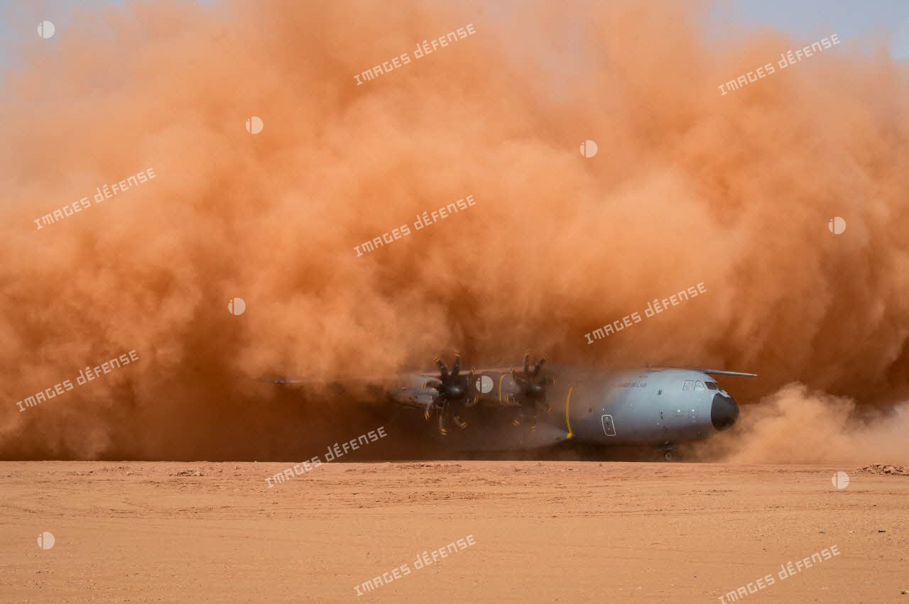 Atterrissage d'expérimentation d'un avion A400M sur la piste de Madama, dans un nuage de poussière ocre.
