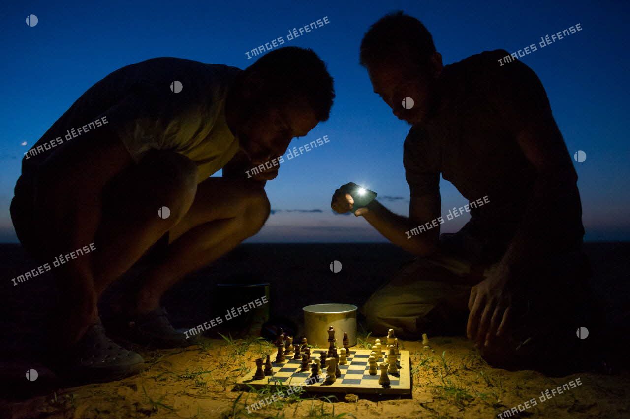 Des éléments du détachement de liaison et d'appui opérationnel n°3 (DLAO 3) disputent une partie d'échecs nocturne dans le désert malien.