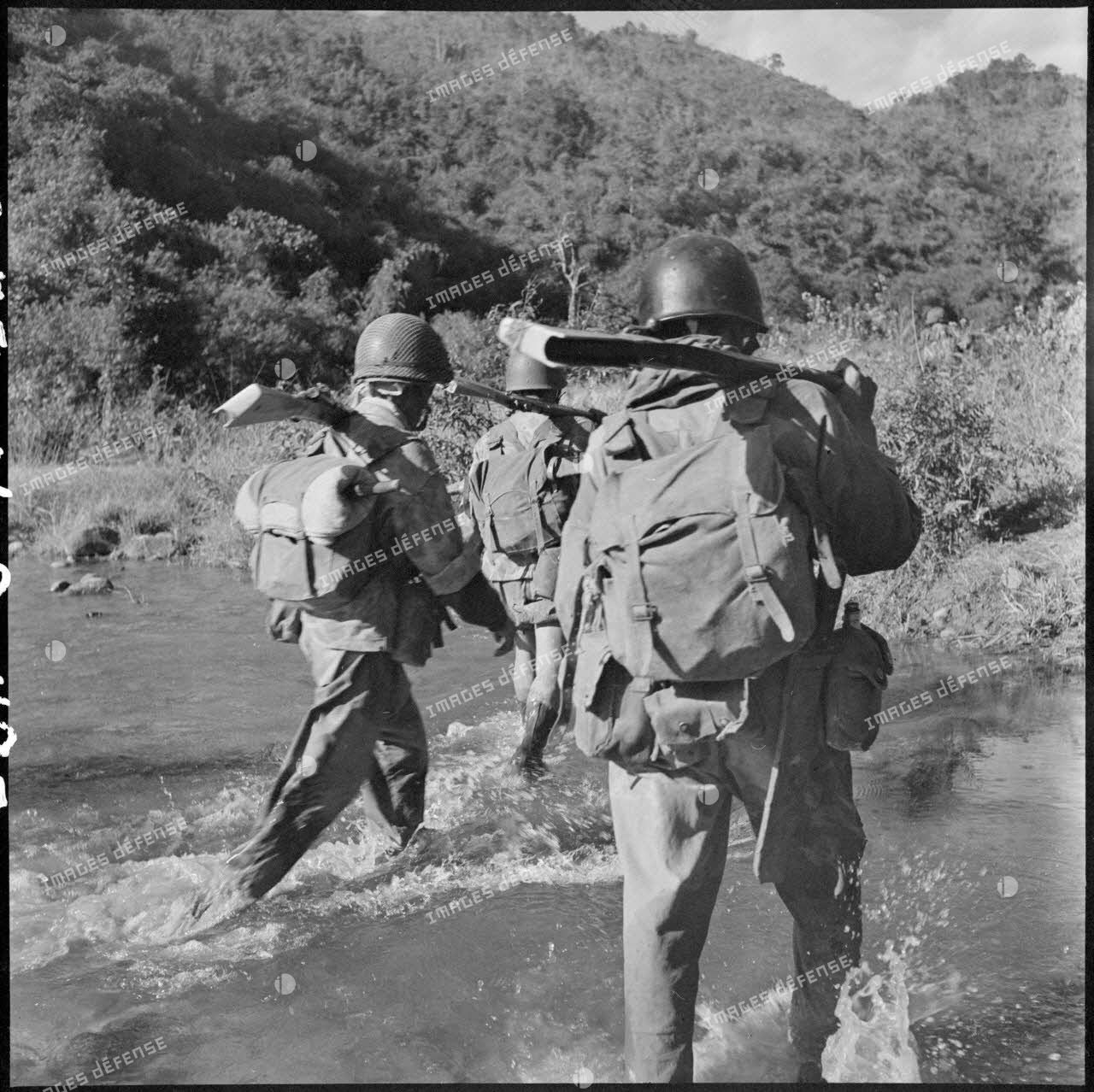Traversée d'un ruisseau de montagne par les parachutistes de la colonne Langlais se dirigeant vers le Laos.