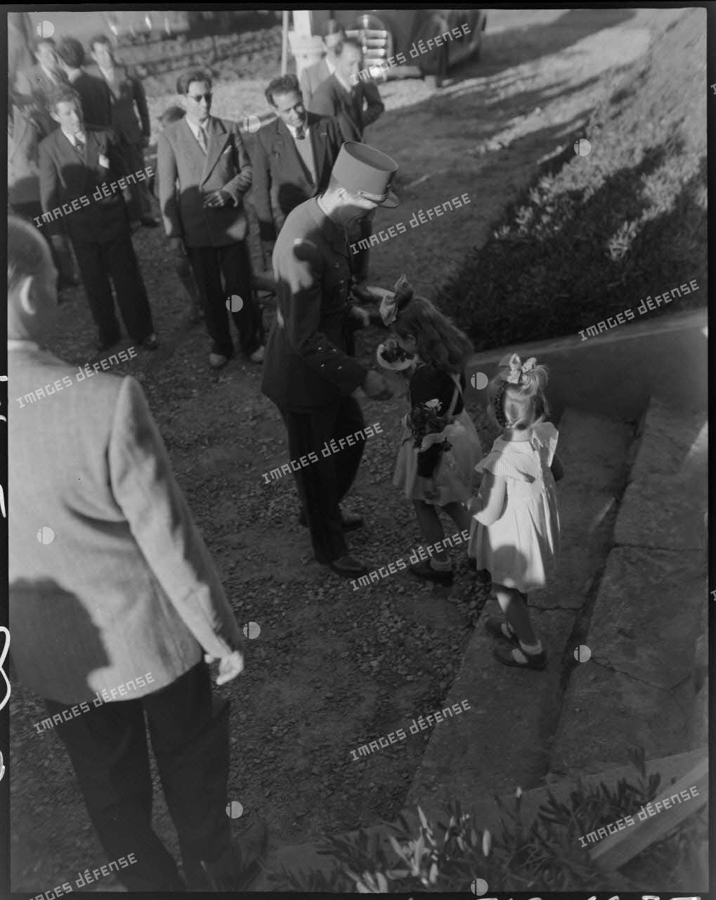Deux petites filles offrent des fleurs au général Philippe Leclerc, en visite à l'Auberge de Provence, à Alger.