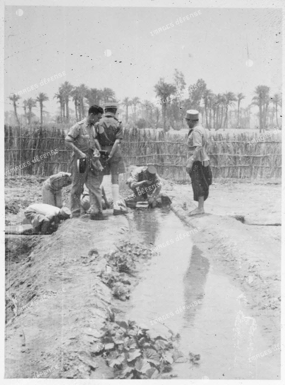 Le général Philippe Leclerc boit de l'eau collectée dans un fossé, sous le regard d'autorités militaires et d'un riverain, au Fezzan.