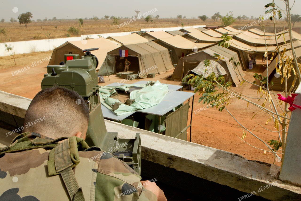 Poste d'observation surplombant le camp du 3e RIMa sur le toit d'un bâtiment aux abords de l'aéroport de Bamako. Une sentinelle observe les alentours à l'aide du dispositif de visée et de localisation d'un poste de tir Eryx sur trépied.