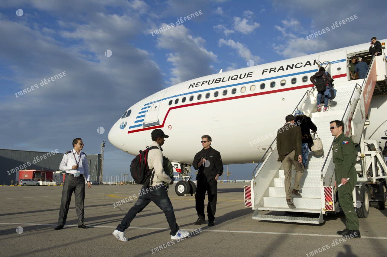 Embarquement de ressortissants évacués par la passerelle de l'Airbus A340 de l'escadron de transport 3/60 Esterel sur l'aéroport de Tripoli (Libye), sous les regards d'un capitaine membre de l'équipage et d'un agent du ministère des Affaires étrangères.