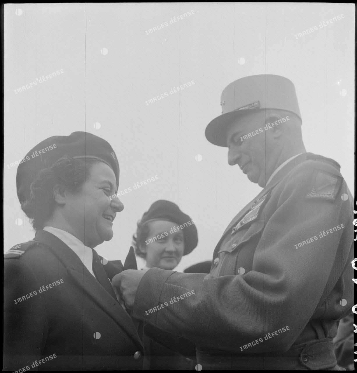 Le général de Linarès décore une femme-soldat, chef de détachement PFAT-Tonkin, lors de la  prise d'armes du PFAT(personnel féminin de l'armée de Terre) au stade Mangin.